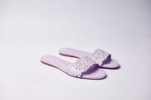 Load image into Gallery viewer, A pair of lavender flat slide sandals with a wide cutout strap, shown on a clean light gray studio background.
