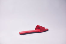 Load image into Gallery viewer, A single red slide sandal with a flat sole, photographed from a side profile against a clean, light gray studio background.